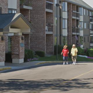 Two people walking outside a brick apartment building.