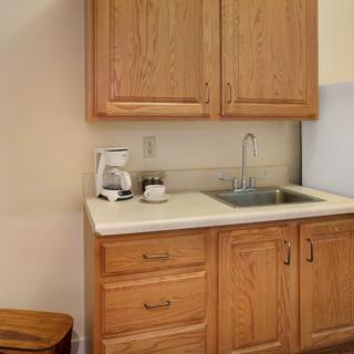A small kitchen area with wooden cabinets, a sink, and a coffee maker on the countertop.