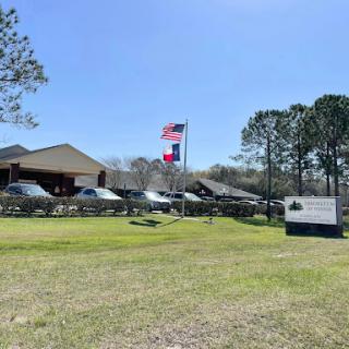 A view of a building with flags flying, surrounded by greenery and under a clear blue sky.