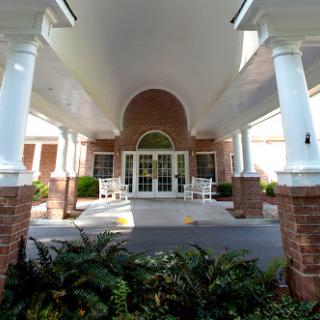 The elegant entrance of a residential building framed by columns and lush greenery.