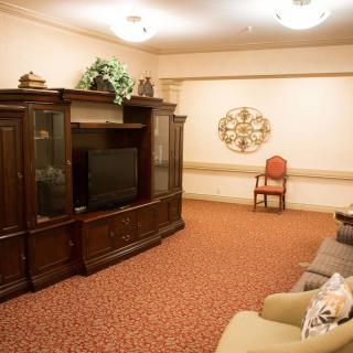 A cozy living room featuring a large wooden cabinet with a TV, comfortable seating, and warm decor.