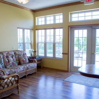 A bright and airy living room with large windows and a floral-patterned sofa.