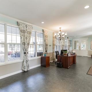 A spacious office interior with a desk, chandelier, and large windows.