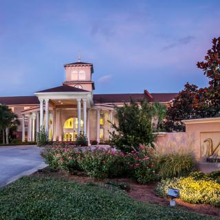 A beautifully lit resort entrance with columns and landscaped gardens at dusk.