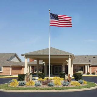 A building entrance with an American flag prominently displayed on a tall flagpole.