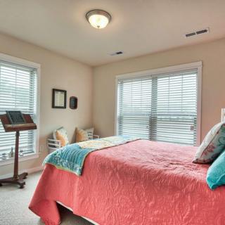 A cozy bedroom with a colorful bedspread and ample natural light coming through the windows.