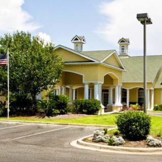 A well-maintained building surrounded by greenery with a parking lot and an American flag nearby.