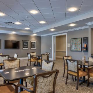 A modern dining area with tables and chairs, featuring a clean interior design and ceiling lights.