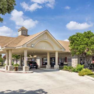 A welcoming entrance of a hospitality building under a clear blue sky.