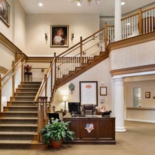 A spacious office interior featuring a grand staircase, a reception desk, and elegant decor.