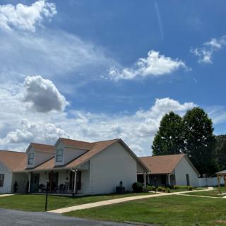 A row of suburban houses under a blue sky with scattered clouds.