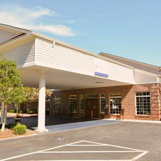 A building with a covered entrance and adjacent parking lot.