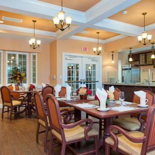 An elegantly decorated dining room with wooden tables and chairs set for a meal, featuring warm lighting and tasteful decor.