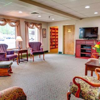 A cozy living room with comfortable seating, a television, and large windows allowing natural light.