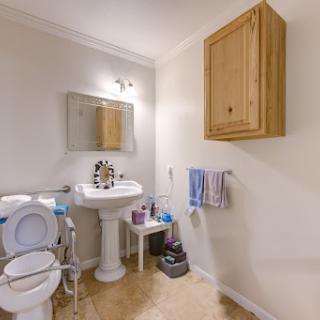 A clean and simple bathroom featuring a toilet, sink, and wooden storage cabinet.