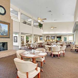 A spacious and modern dining area with neutral decor, featuring tables and chairs.