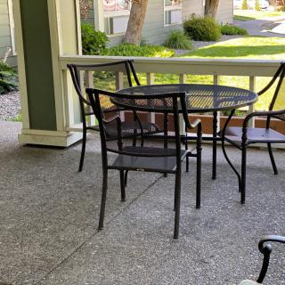 A peaceful porch with a set of outdoor chairs and table overlooking a garden.