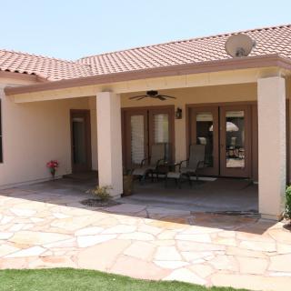 A residential patio area with outdoor seating and tiled flooring under a covered structure.