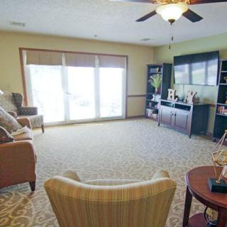 A spacious living room with comfortable seating, a large window, and a television.