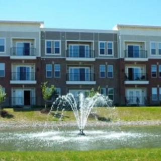 A view of a modern apartment building with a fountain in the foreground.