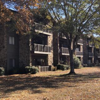 A residential apartment building with balconies surrounded by trees and fallen leaves.