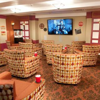 A cozy lounge area with patterned chairs facing a large television.