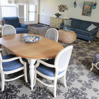 A cozy living and dining area featuring a wooden table with chairs, a blue sofa, and a patterned rug.