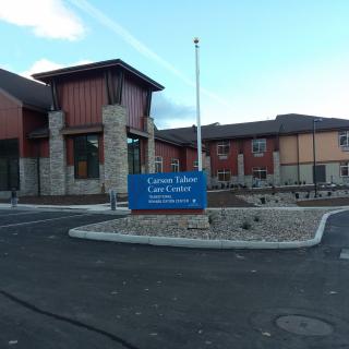 Entrance view of a modern library with a sign and parking area.