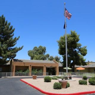 A building entrance with a flagpole displaying the American flag on a sunny day.