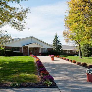 A suburban house with a landscaped driveway lined with flowers and trees.