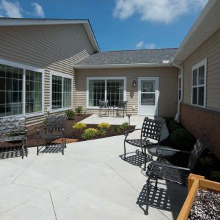 A sunny outdoor patio area with seating and landscaping, surrounded by residential buildings.