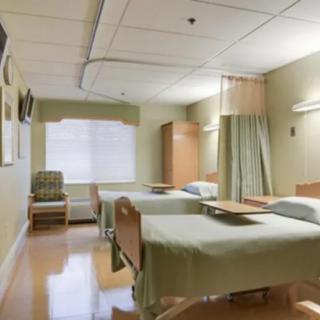 A clean and well-organized hospital room with two patient beds and privacy curtains.