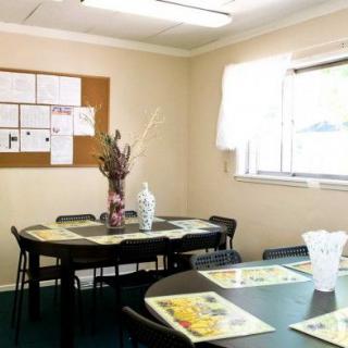A small meeting room with a conference table and chairs, featuring a window and bulletin board.