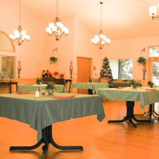 A cozy dining area featuring neatly arranged tables, elegant chandeliers, and festive decorations.