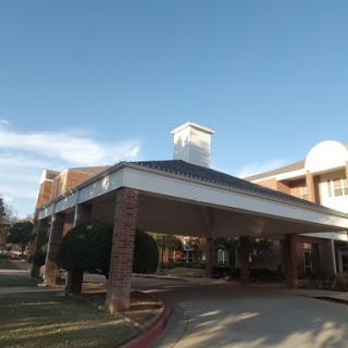 A welcoming entrance to a residential facility with a classic architectural design under a clear blue sky.