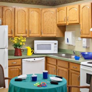 A cozy kitchen with wooden cabinets, modern appliances, and a small table set for coffee.