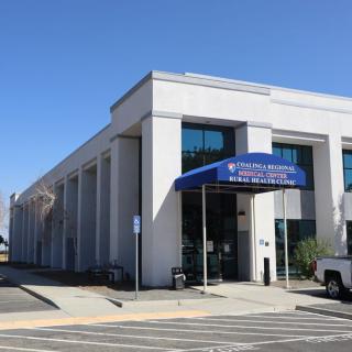 The exterior of a commercial bank building with a blue awning at the entrance.