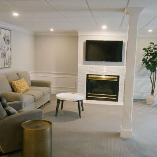 A cozy and modern living room featuring a comfortable sofa, wall-mounted television, and a fireplace.