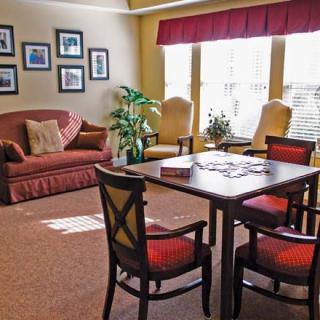 A cozy living room with a sofa, chairs, and a table near a window with curtains.