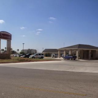 A view of a commercial building with a parking lot and a prominent sign under a clear blue sky.