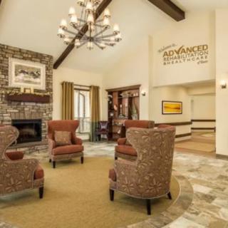 A cozy lobby area with comfortable chairs, a fireplace, and a chandelier.