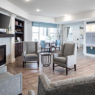 A modern living room with stylish furniture, featuring a cozy seating area around a fireplace and ample natural light.