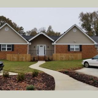 A suburban brick house with a lawn and driveway.
