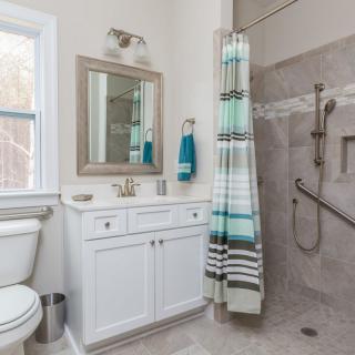 A modern bathroom with a shower area, vanity, and striped shower curtain.
