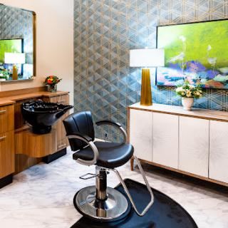 A stylish and modern hair salon interior featuring a sleek barber chair, wash station, and contemporary decor.
