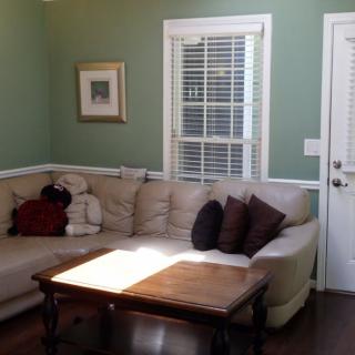 A cozy living room with a sectional sofa, coffee table, and sunlit window.