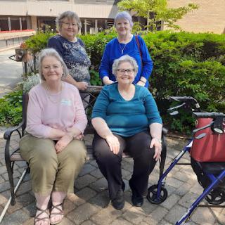 A joyful gathering of four women enjoying a sunny day outdoors.
