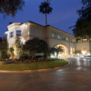 A well-lit house at night with a landscaped driveway.