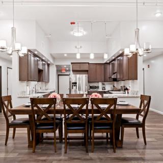 A modern dining area with a wooden table set and sleek kitchen in an open-concept space.