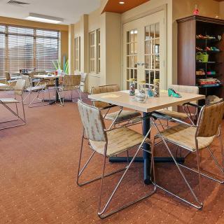 A modern cafe interior with wooden tables and chairs under bright lighting.